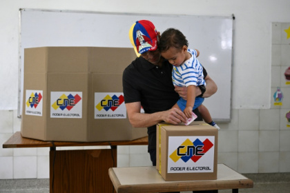 Venezuelan opposition candidate Henrique Capriles casts his vote while holding his son at a polling station in Caracas - Federico PARRA (AFP)