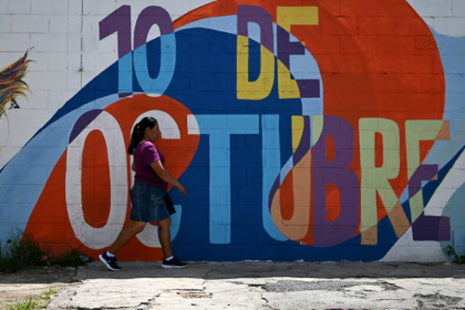 A woman walks in front of a mural in the 10 de Octubre district, a former gang stronghold in El Salvador - Marvin RECINOS (AFP)