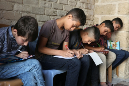 Palestinian children take notes as they attend a class in the historic Al-Kamaliya al-Othmanya school in Gaza City's Old Town, as part of a volunteer initiative organised by displaced teachers, in Gaza City - Omar AL-QATTAA (AFP)