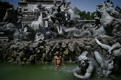 A man cools off in the basin of the Girondins Fountain in Bordeaux - Philippe LOPEZ (AFP)